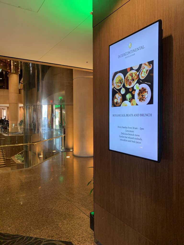 Portrait digital screen on a timber wall in the InterContinental Adelaide foyer, promoting Sunday brunch