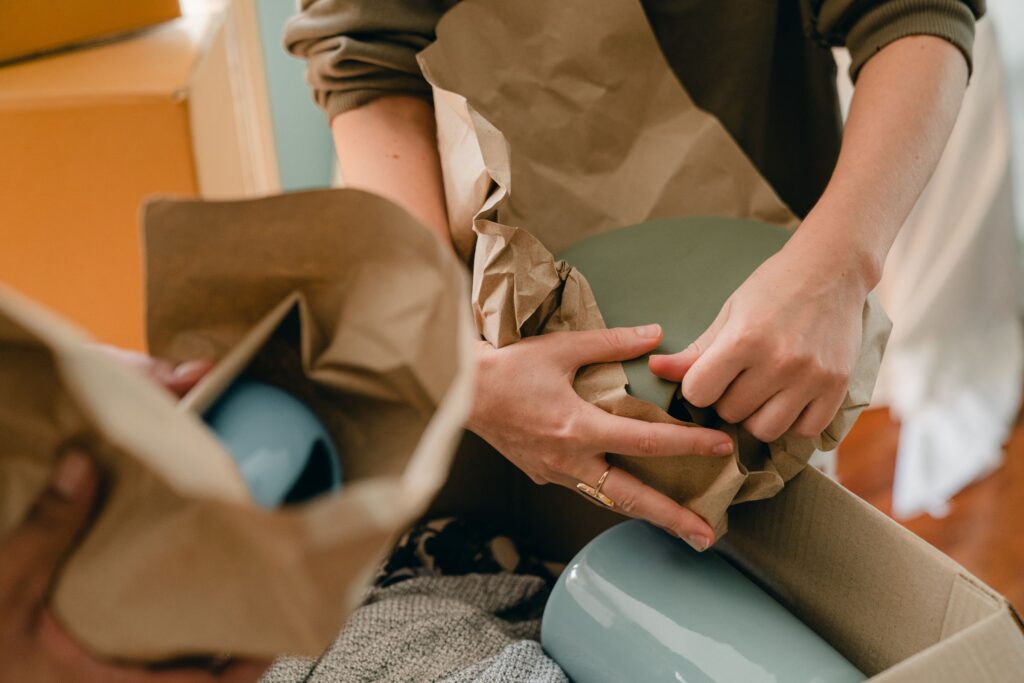Hands packing an online order into a cardboard box