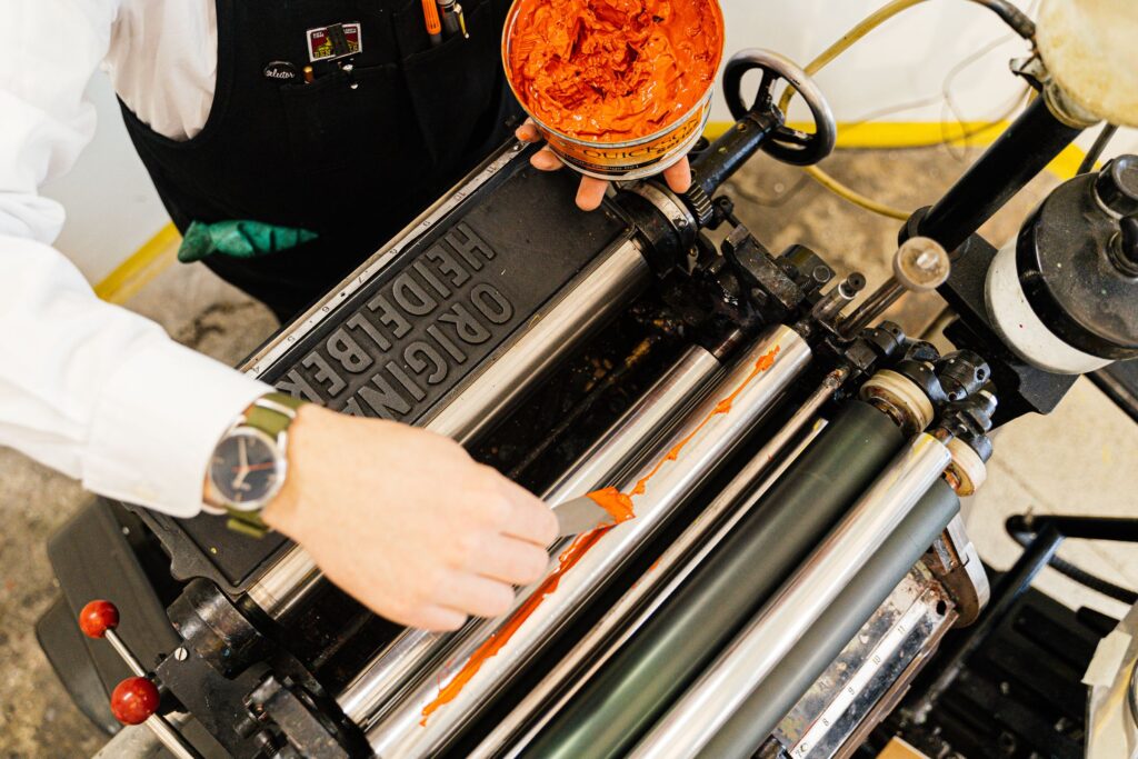 Hands inking a vintage printing press